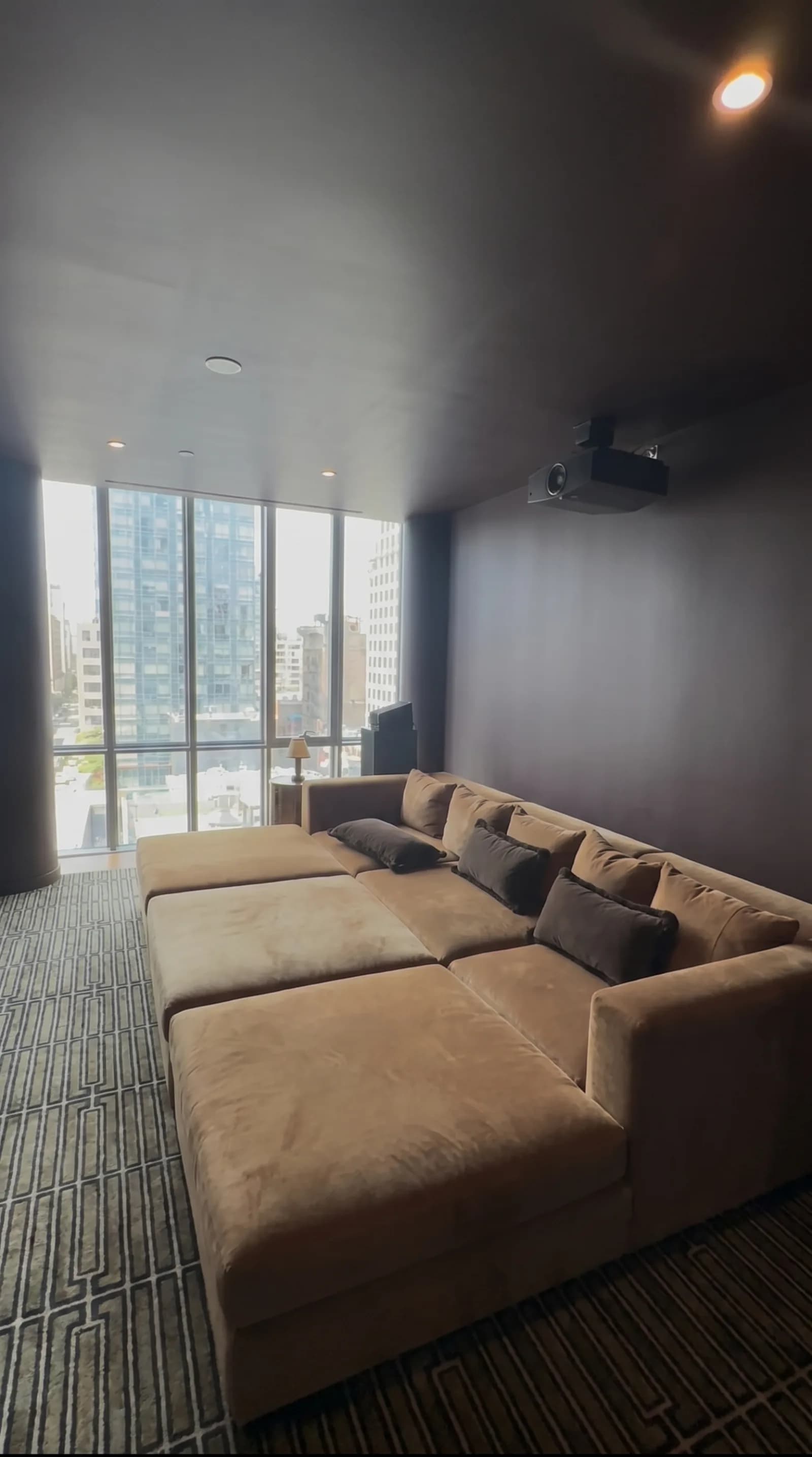 NYC home theatre with a ceiling projector, plush sectional seating and a city skyline view