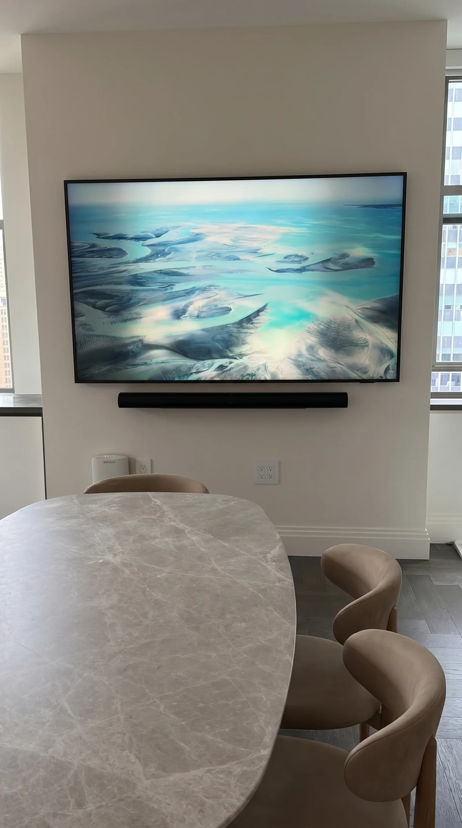 Wall-mounted TV with a soundbar in a marble dining room