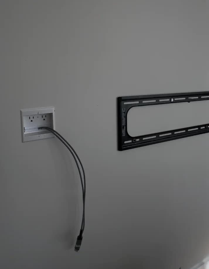 In-wall power outlet and recessed cable plate behind a TV mount