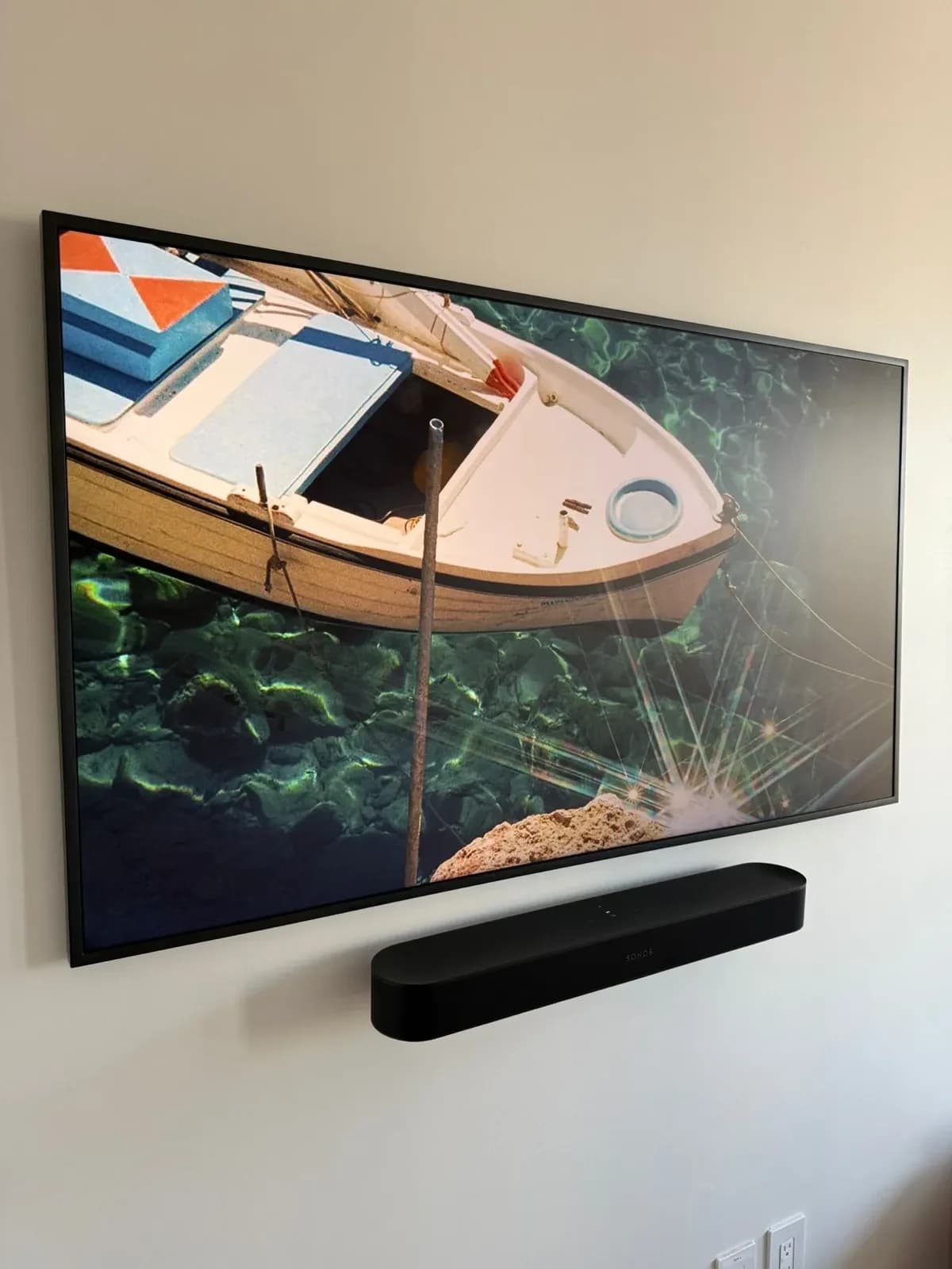 Large flat-screen TV wall-mounted flush above a Sonos soundbar on a beige living room wall