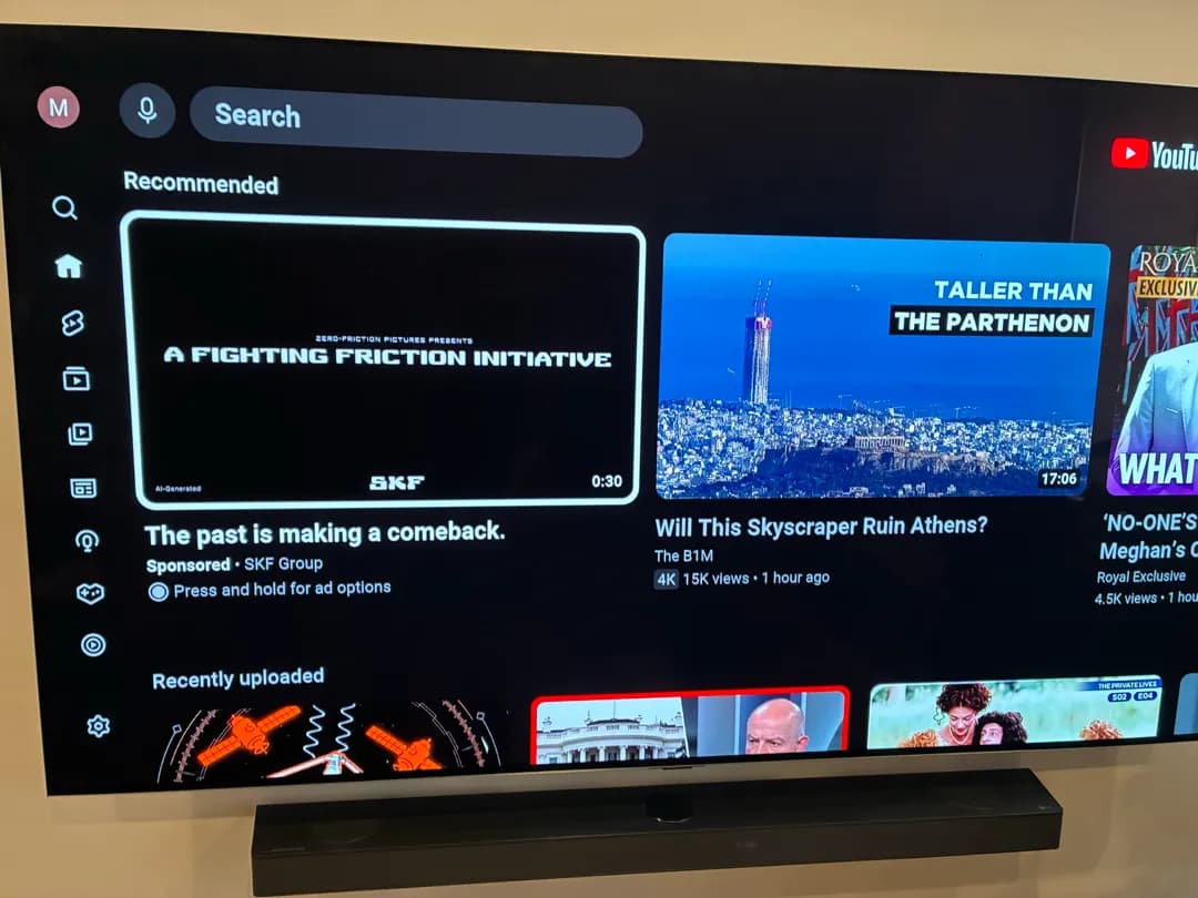 wall-mounted TV displays a YouTube recommendations screen above a soundbar.