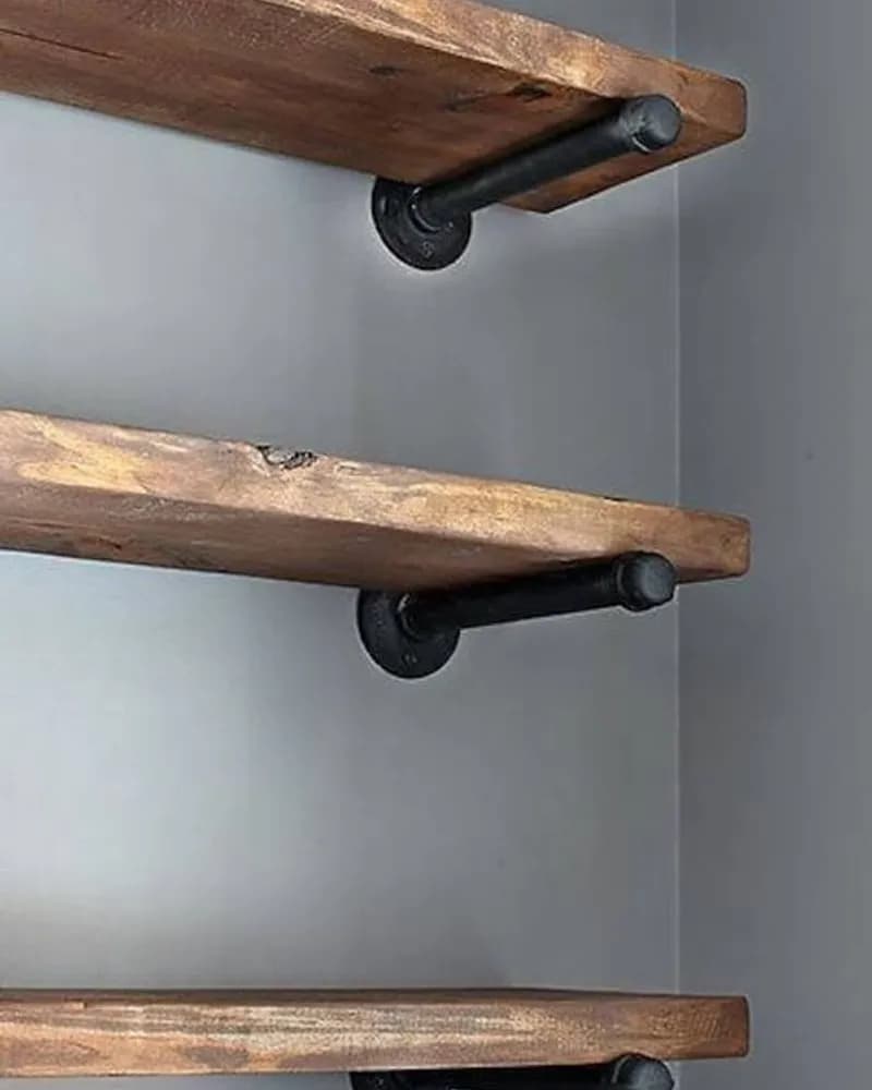 Three wooden shelves mounted to a wall with black pipe brackets