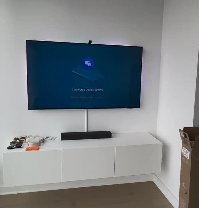 Large TV wall-mounted above a floating white media console and soundbar in a minimalist NYC apartment