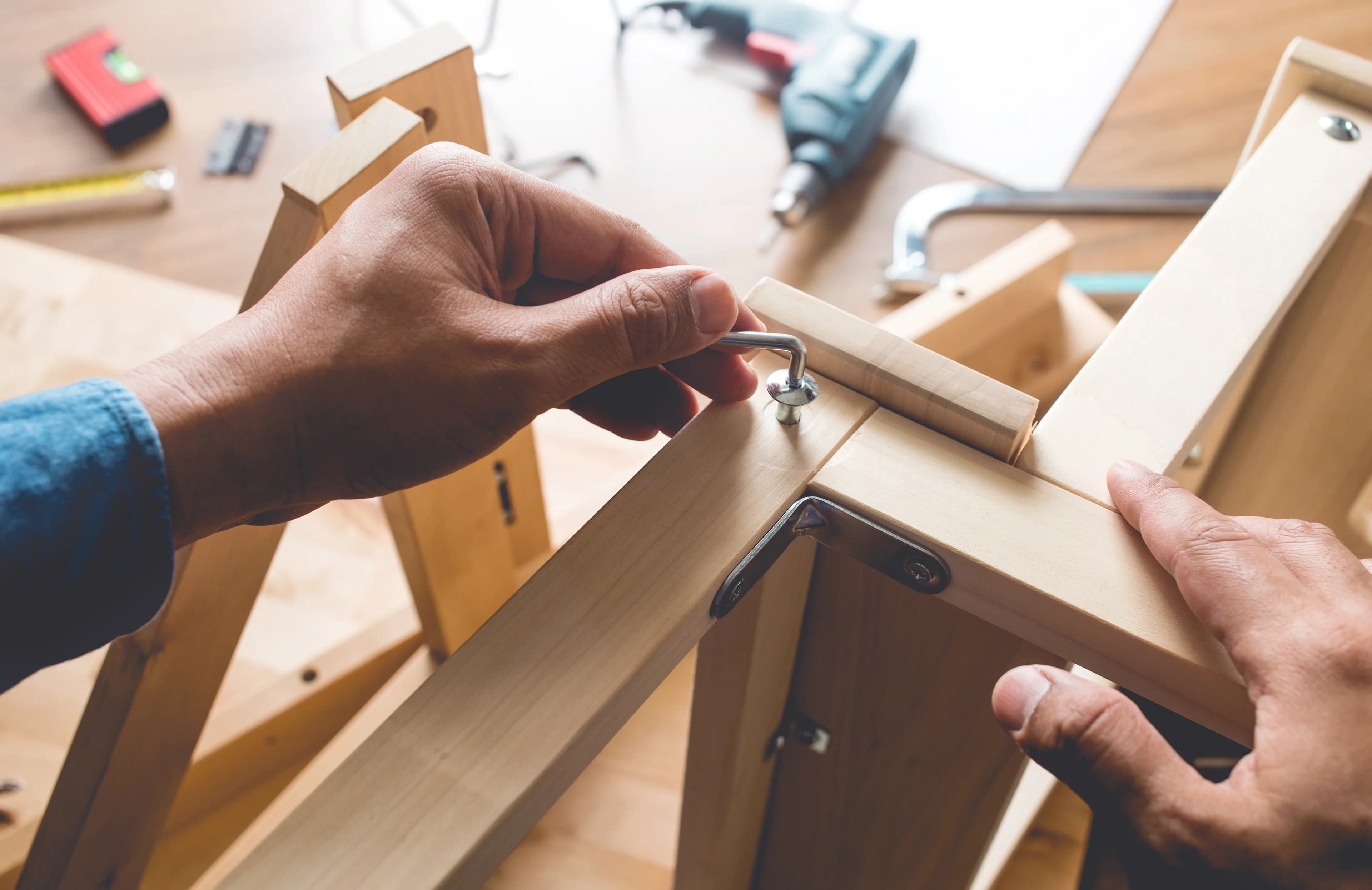 Hands tightening a fastener while assembling a wooden television stand