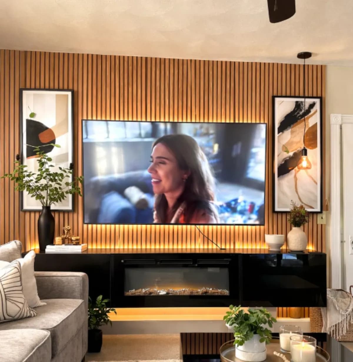 TV mounted on a wood-slat feature wall above a floating electric fireplace and LED underglow in a living room