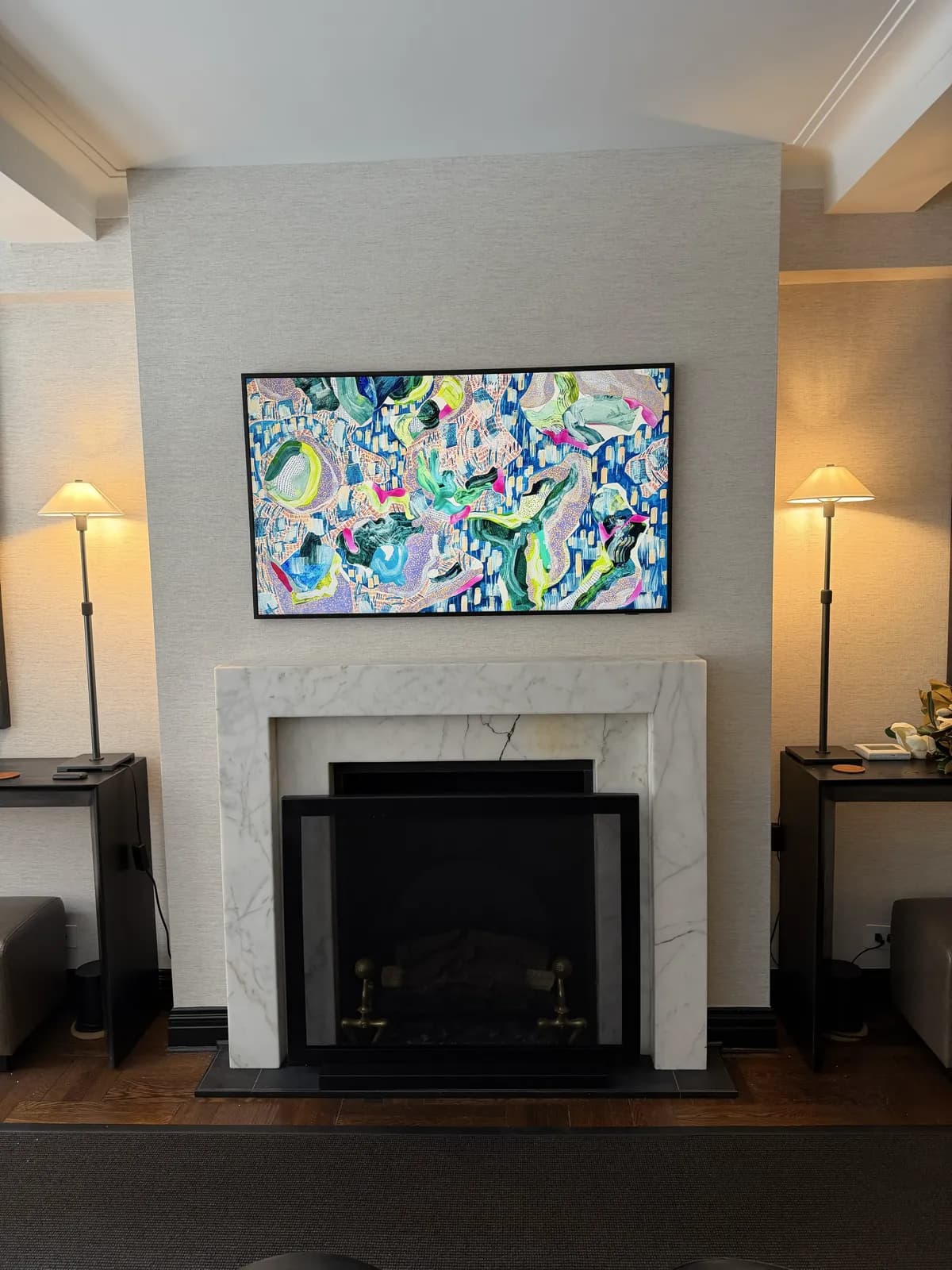 Frame TV displaying colorful art mounted above a marble fireplace mantel in an NYC living room