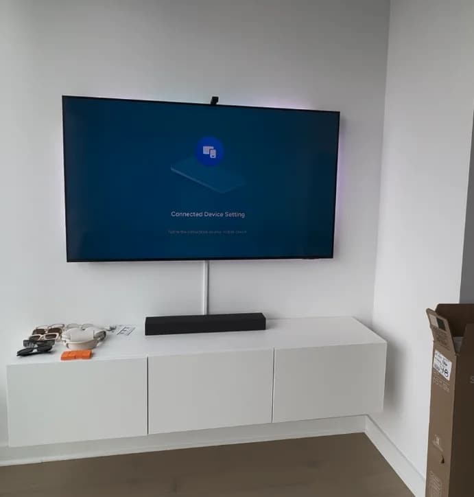 Large TV wall-mounted above a floating white media console and soundbar in a minimalist NYC apartment