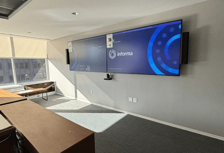 Dual wall-mounted displays with video conferencing camera bar installed in a corporate meeting room