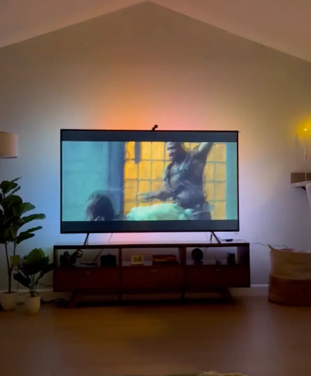 TV with rainbow bias-lighting LED strip glowing behind it on a media console in a cozy living room at night