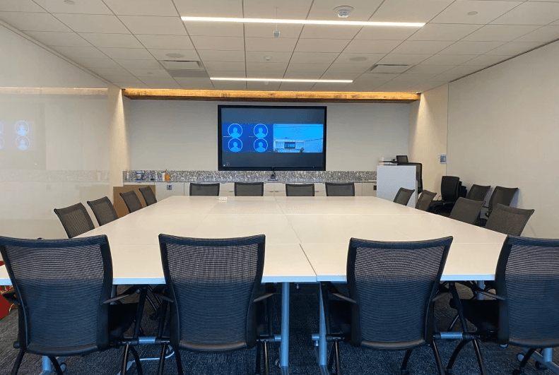 Corporate boardroom with a dual-display video conferencing setup and U-shaped conference table
