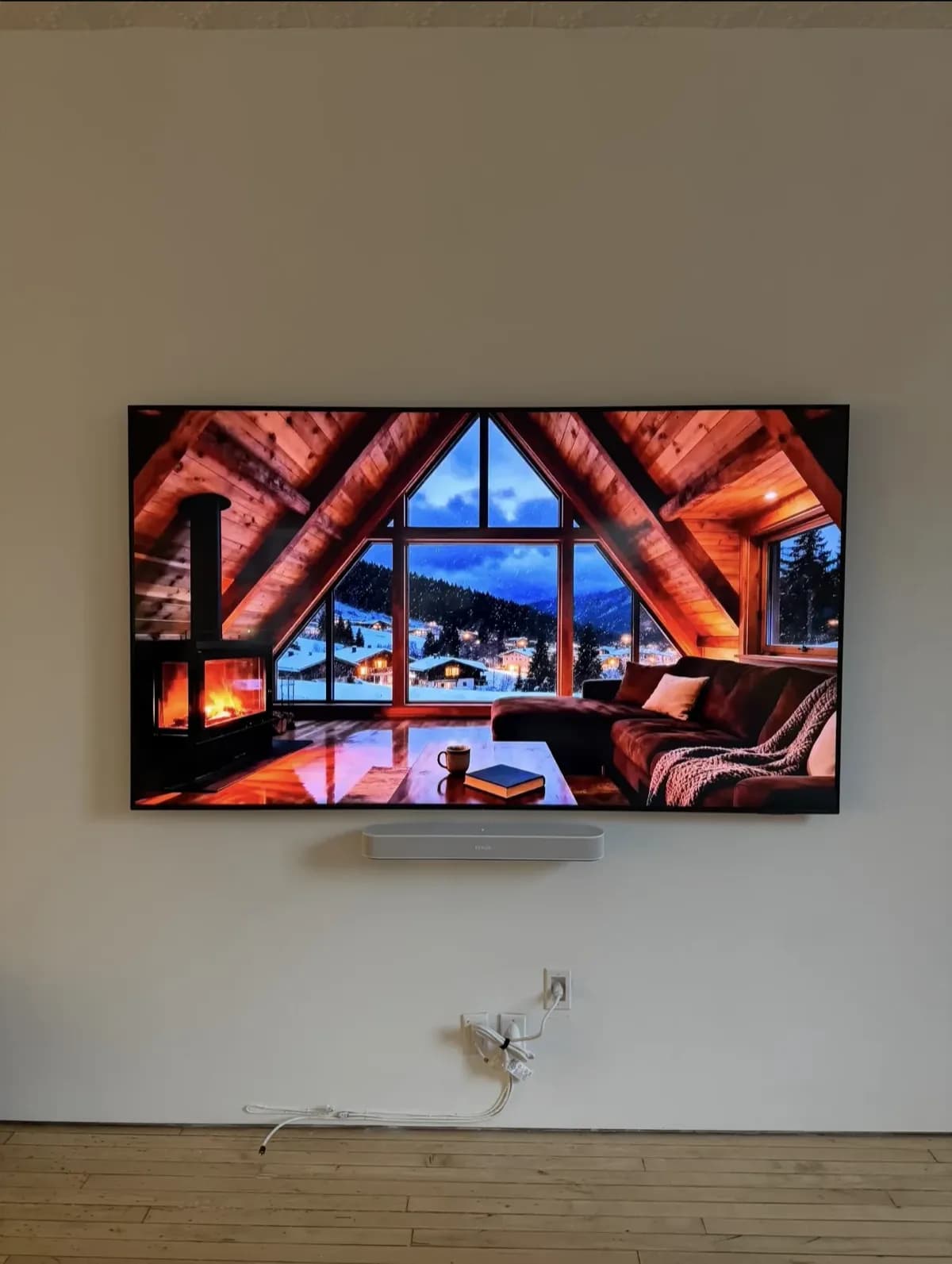 Large flat-screen TV wall-mounted above a wall-hung soundbar with power bridge concealing all cables behind the wall
