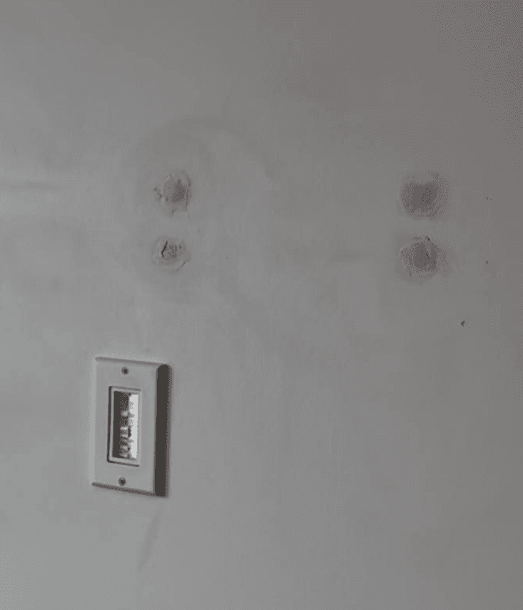 Wall after TV dismounting showing four patched screw holes with DryDex filler ready for paint touch-up