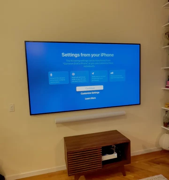 Large TV wall-mounted above a mid-century media console with power and cables fully concealed in the wall