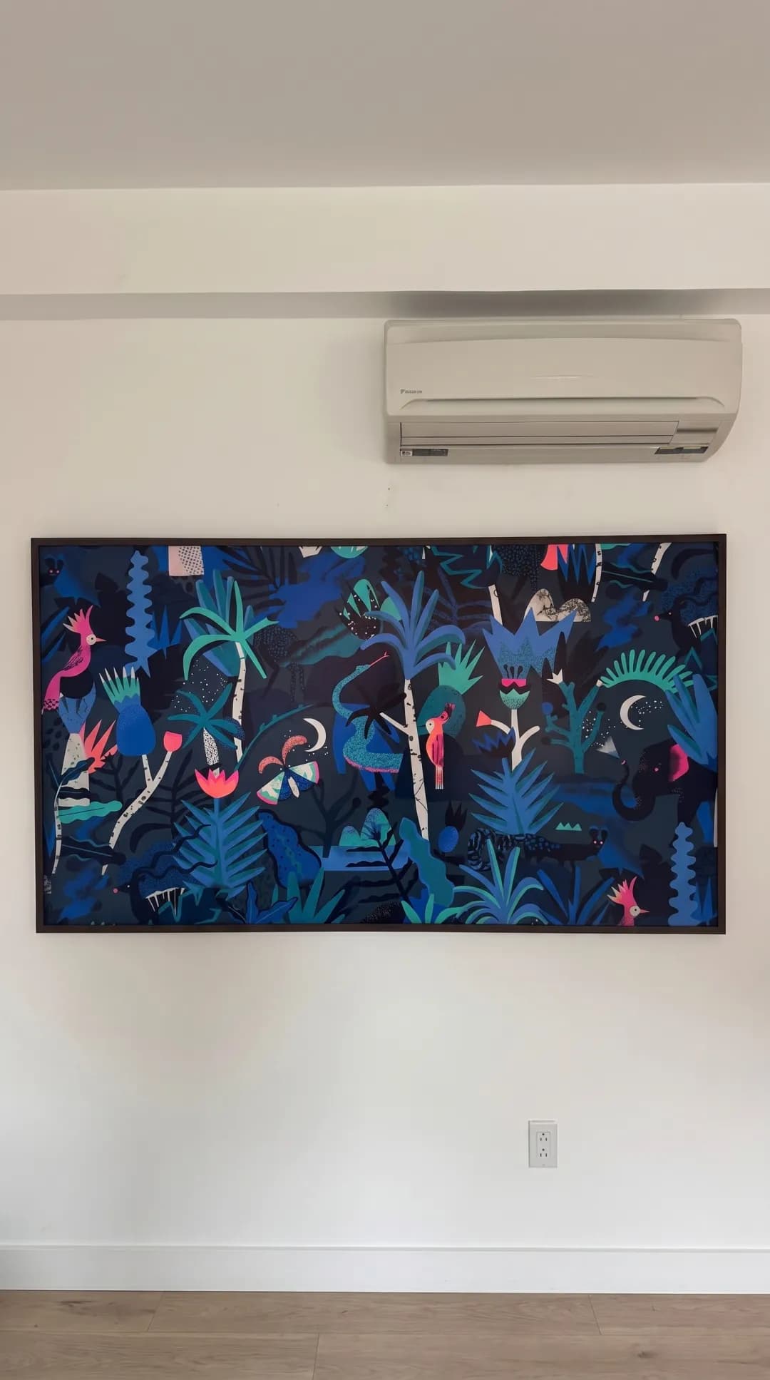 TV in Art Mode wall-mounted beside a tropical plant and a mini-split unit
