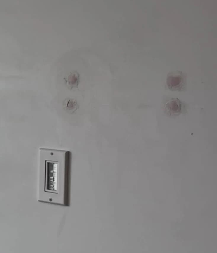 Wall after TV dismounting showing four patched screw holes with DryDex filler ready for paint touch-up