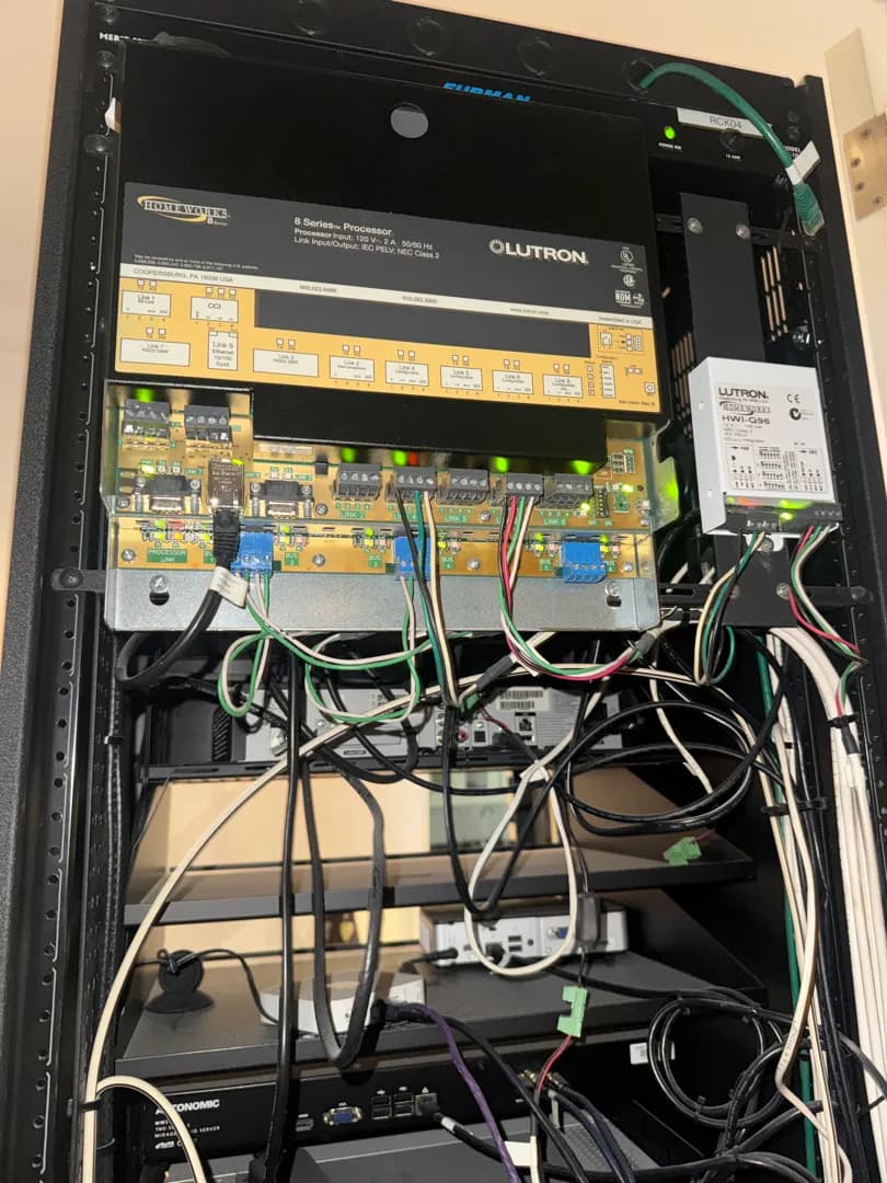 A Lutron home lighting-control processor and its wiring, mounted in the same equipment rack as the audio gear.
