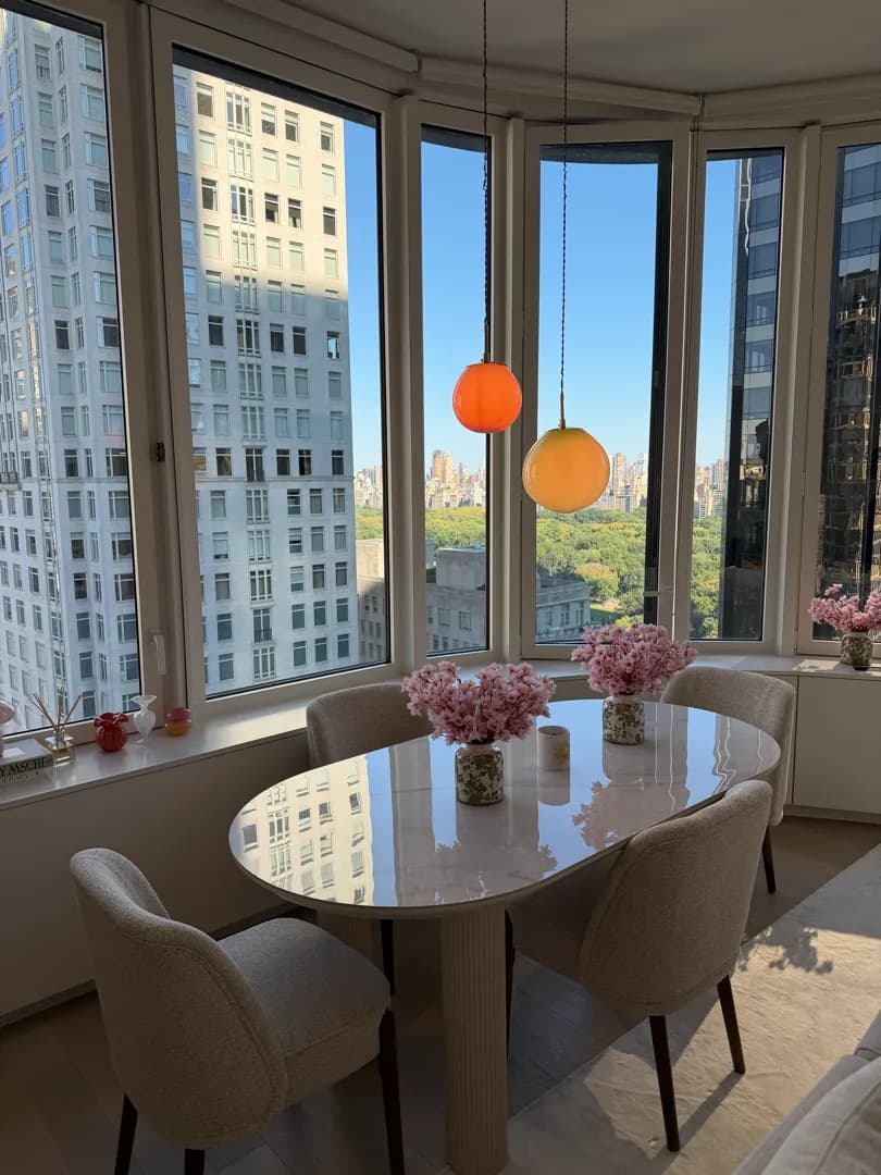 Two glass globe pendants hanging over the oval dining table in front of the curved windows.