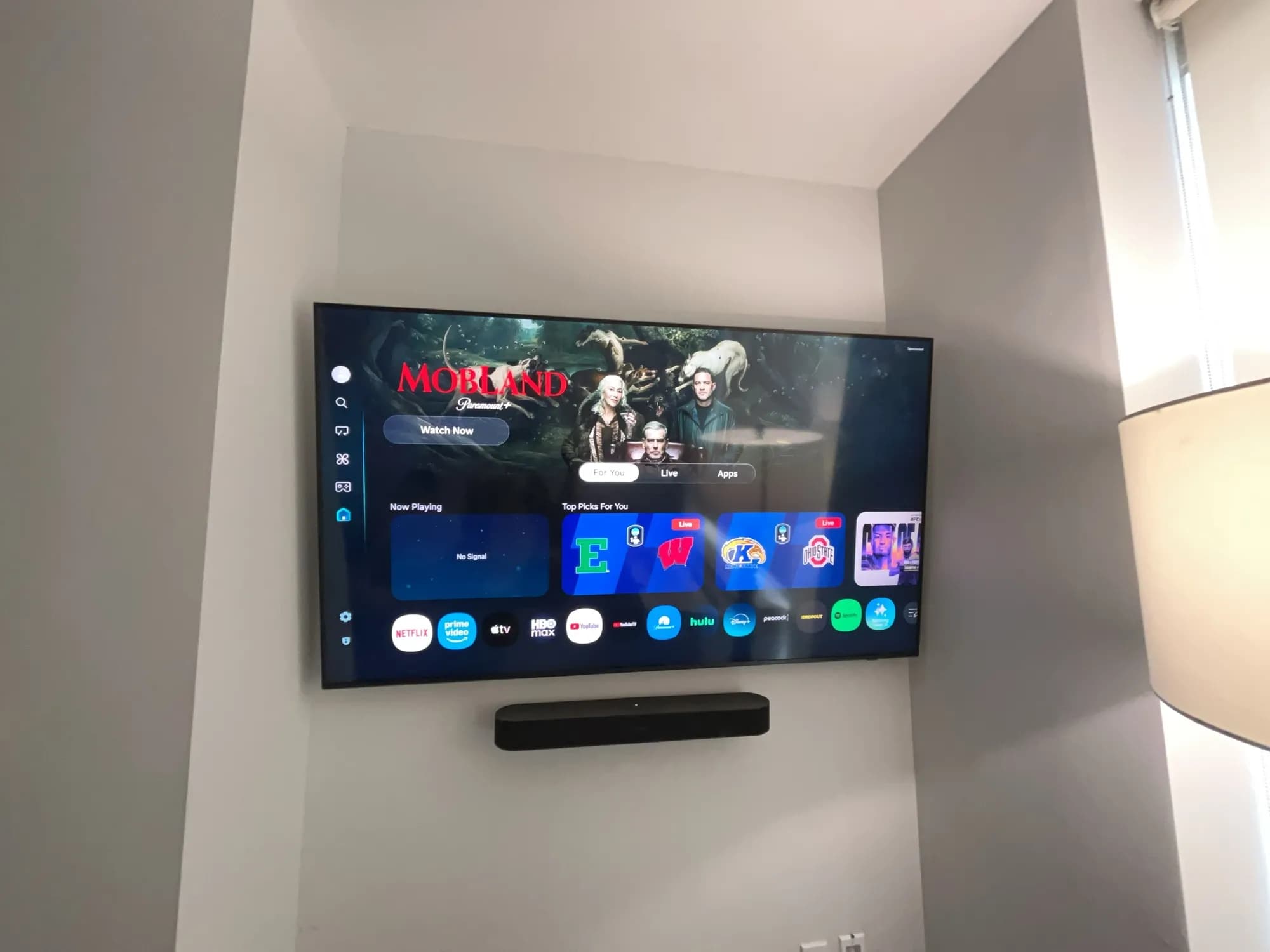 A wall-mounted TV in a different room showing a streaming home screen, not matching this job's wall.