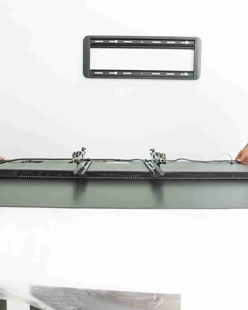 A television being lifted away from its wall bracket