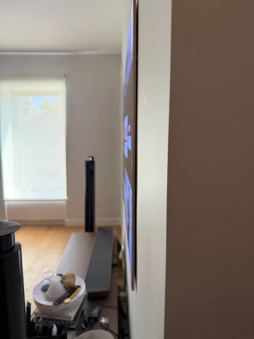 Side view of the LG W6 wallpaper TV beside a window, showing how slim it sits on the wall.