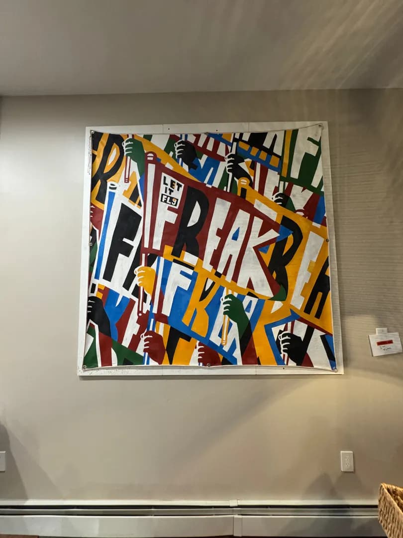 A large, colorful canvas art piece with bold graphic lettering, hung on a plain wall.