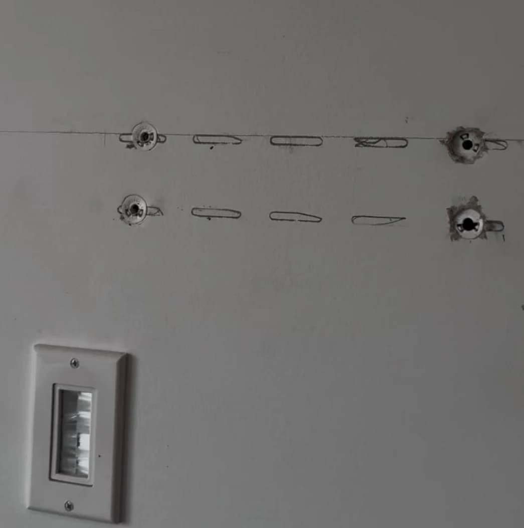 Wall after TV dismounting showing exposed anchor holes ready for patching