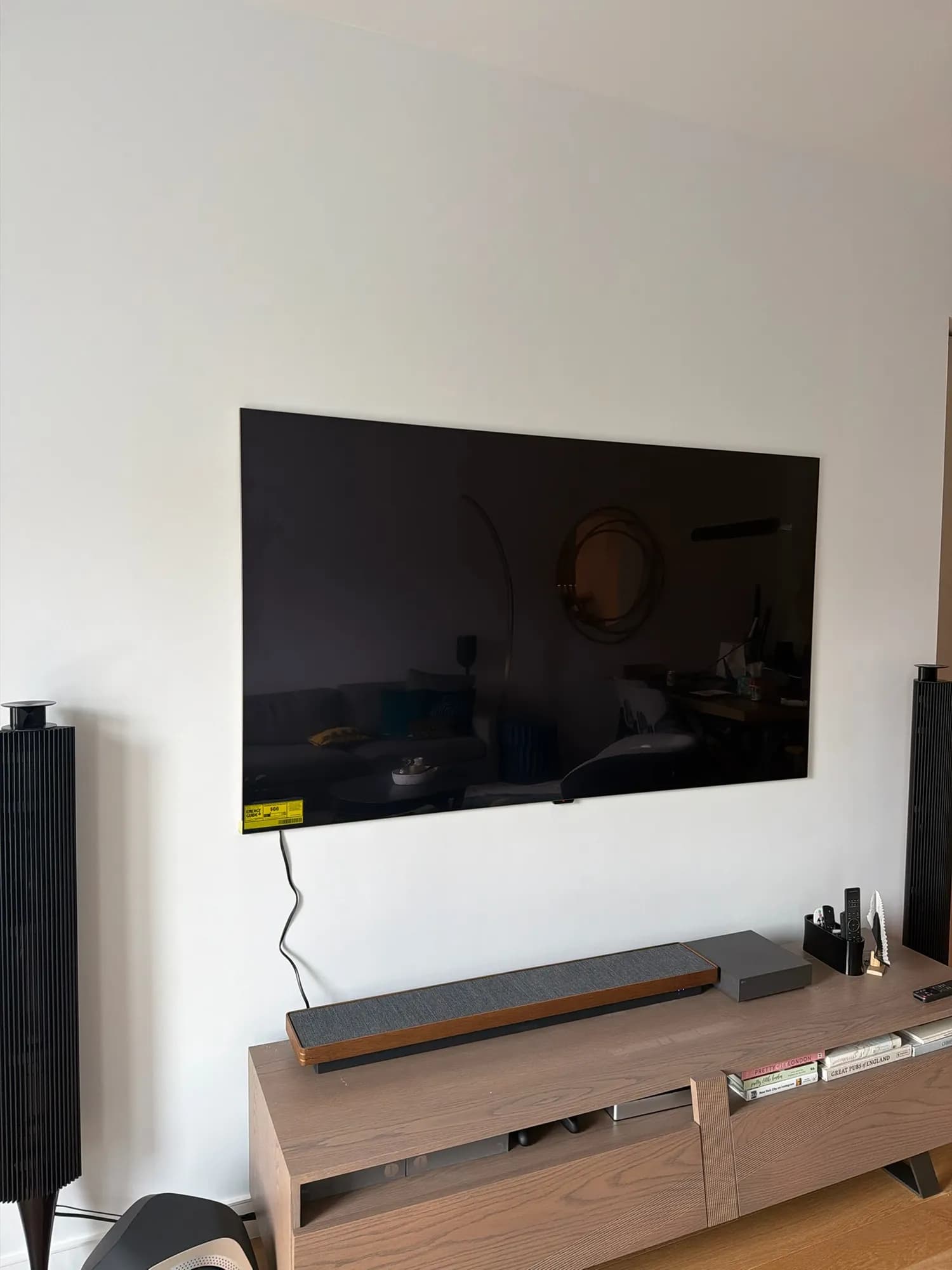 A flush-mounted TV above a wooden console, with a power cord running visibly down the wall to a tag near the bottom edge.