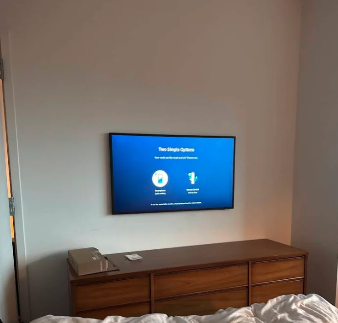 TV mounted on wall above dresser in bedroom, setup screen